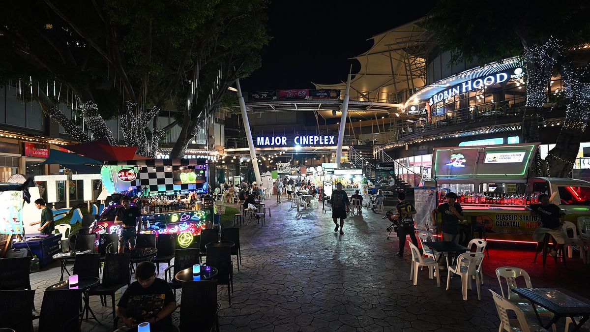 DZ6 1732 A lively outdoor night market and entertainment area lit with colorful neon stalls and signs with a Major Cineplex marquee glowing in the background