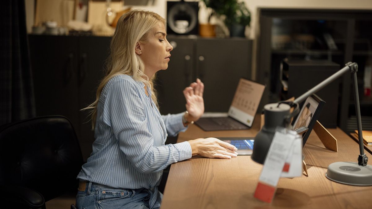 Woman sits at desk working on laptop in home office